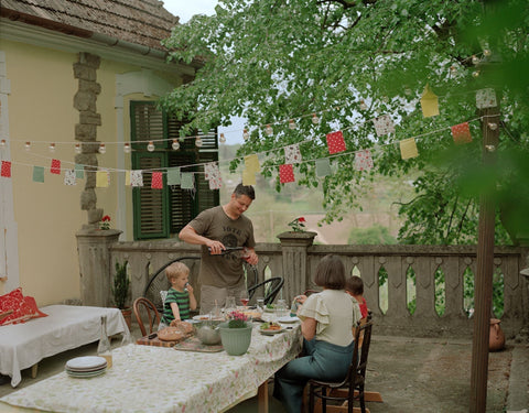 A wine-making couple and their children at a table on a deck